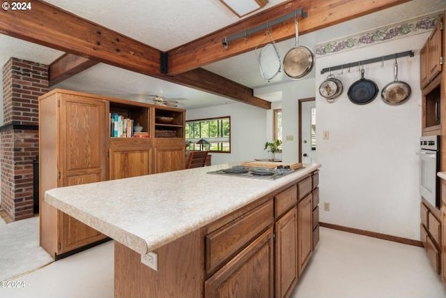 kitchen with stainless steel appliances, light countertops, beamed ceiling, light carpet, and ceiling fan