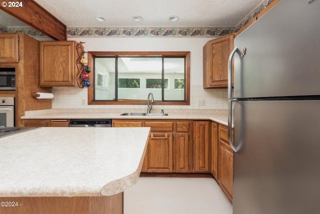 kitchen featuring beam ceiling, sink, appliances with stainless steel finishes, and tasteful backsplash