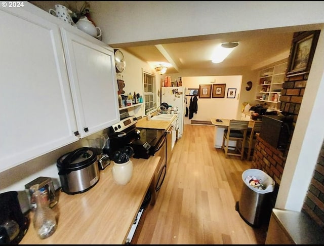 kitchen featuring white refrigerator, light wood-type flooring, and white cabinetry