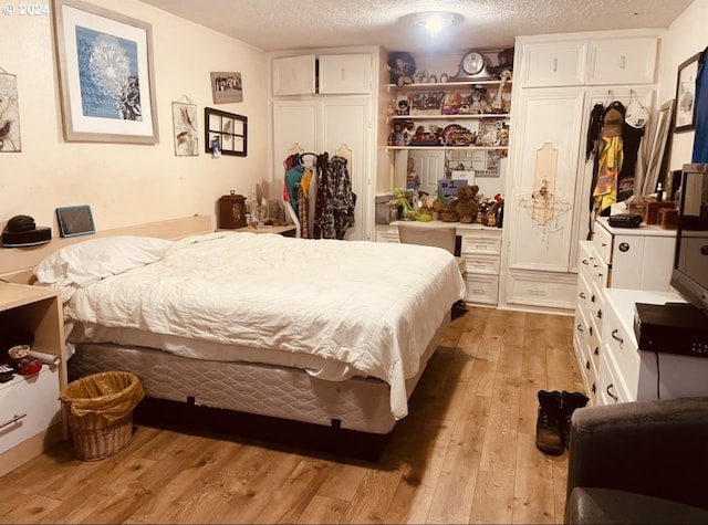 bedroom with a textured ceiling and light hardwood / wood-style flooring