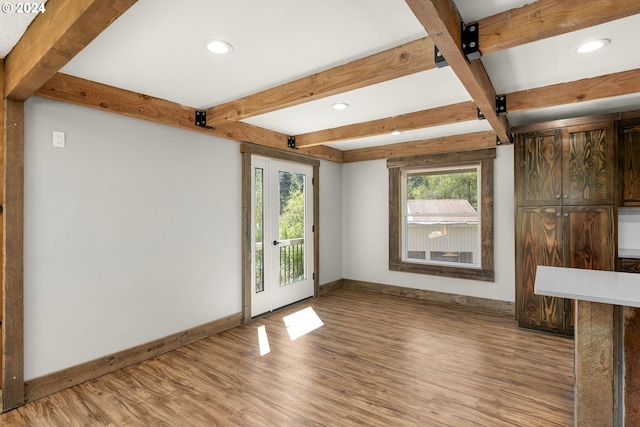 unfurnished living room with beamed ceiling, light hardwood / wood-style floors, and a barn door