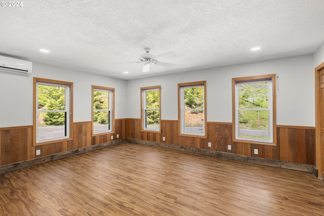 unfurnished room with ceiling fan, plenty of natural light, hardwood / wood-style flooring, and a textured ceiling