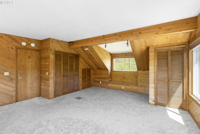 bonus room with wooden walls, carpet floors, and beamed ceiling