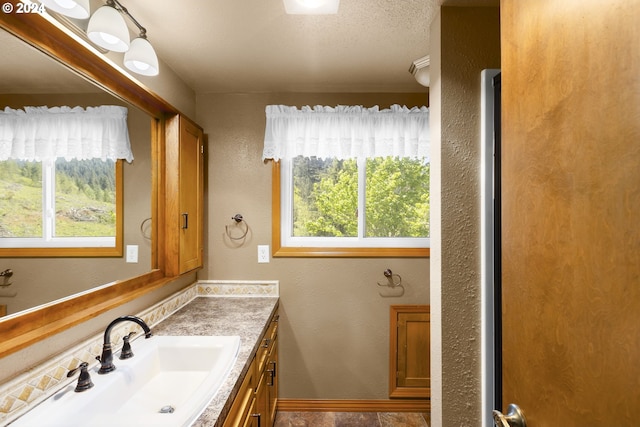 bathroom with plenty of natural light, a textured ceiling, and vanity