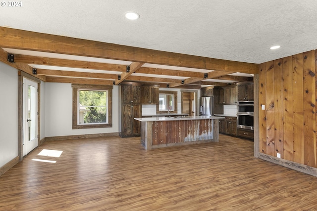 kitchen with a kitchen island, wood-type flooring, appliances with stainless steel finishes, and dark brown cabinetry