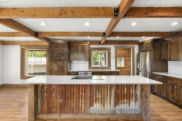 kitchen featuring light hardwood / wood-style floors, tasteful backsplash, beamed ceiling, sink, and stainless steel fridge with ice dispenser