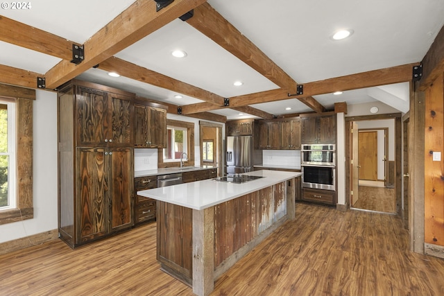 kitchen featuring a center island, stainless steel appliances, dark brown cabinets, wood-type flooring, and tasteful backsplash