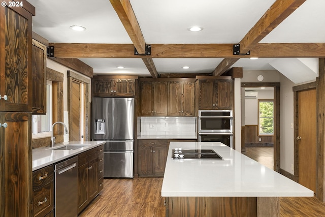 kitchen featuring dark hardwood / wood-style floors, backsplash, a center island, beamed ceiling, and appliances with stainless steel finishes