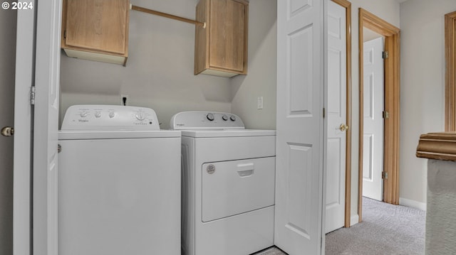 washroom featuring washer and clothes dryer, light carpet, and cabinets