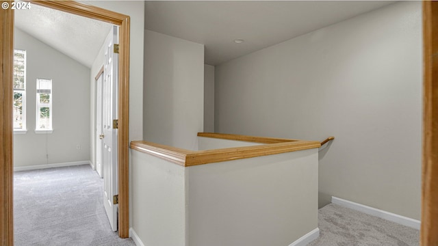 hallway featuring light colored carpet and lofted ceiling