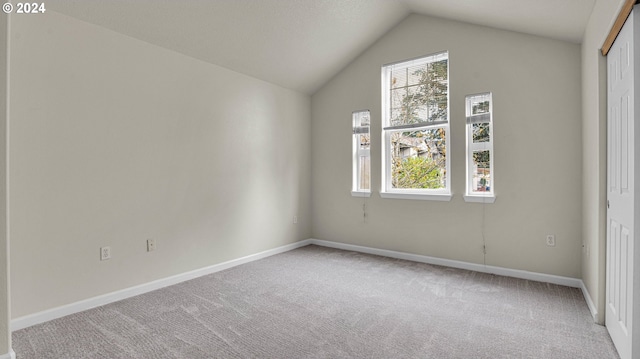 carpeted spare room featuring lofted ceiling