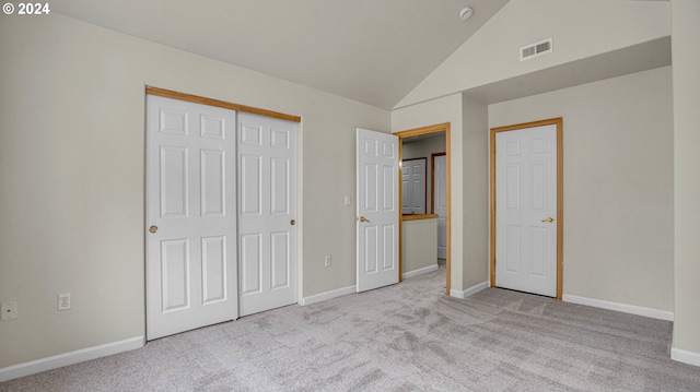 unfurnished bedroom with light carpet, vaulted ceiling, and a closet