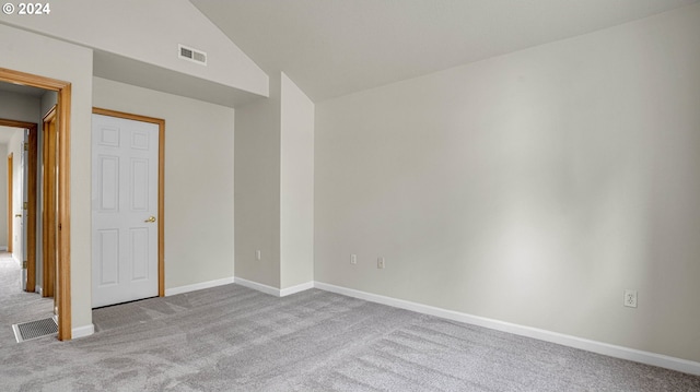 empty room with vaulted ceiling and light colored carpet