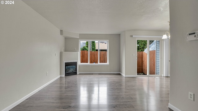 unfurnished living room with a textured ceiling, a notable chandelier, and hardwood / wood-style flooring