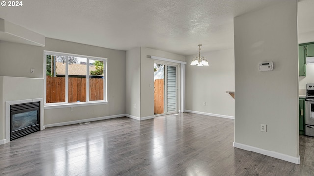 unfurnished living room with hardwood / wood-style flooring, a textured ceiling, and a notable chandelier