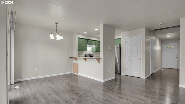 kitchen with stainless steel appliances, a textured ceiling, green cabinets, dark hardwood / wood-style flooring, and a breakfast bar area