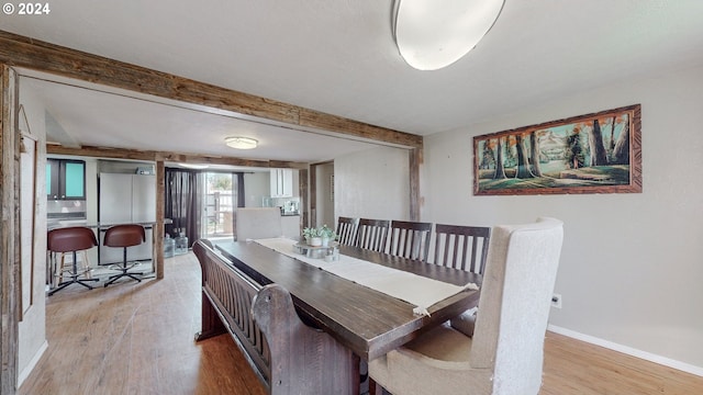 dining area with beamed ceiling and light hardwood / wood-style flooring