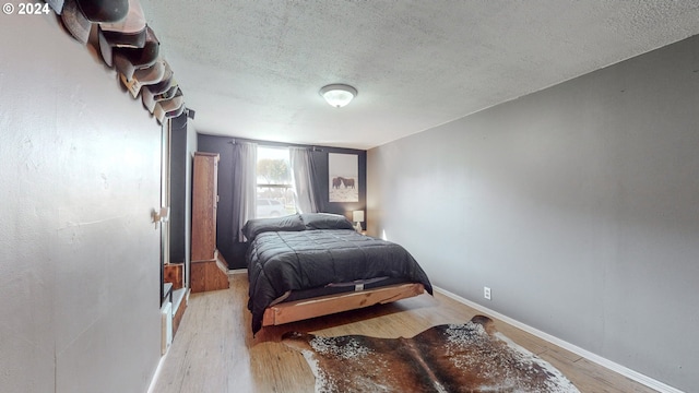 bedroom featuring light wood-type flooring and a textured ceiling