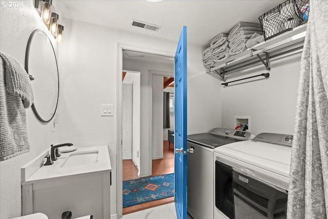 clothes washing area featuring sink and washer and clothes dryer