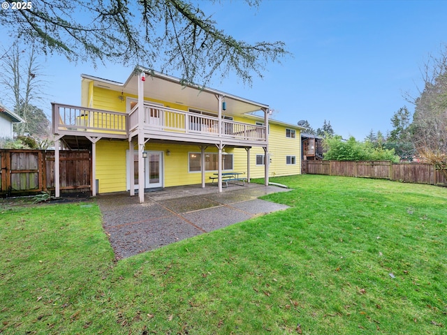 rear view of property featuring a lawn, a wooden deck, and a patio