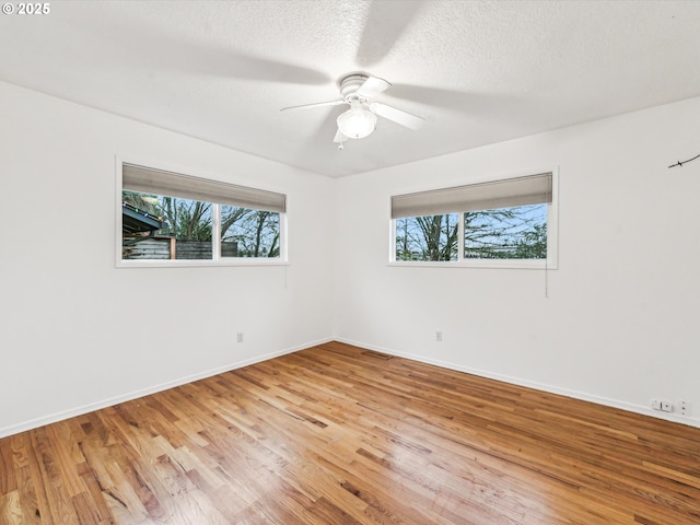 unfurnished room with ceiling fan, a textured ceiling, light wood-style flooring, visible vents, and baseboards