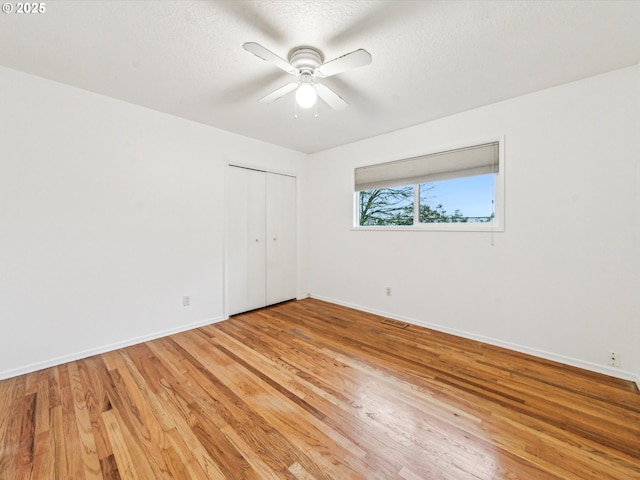 unfurnished room featuring light wood finished floors, visible vents, baseboards, ceiling fan, and a textured ceiling