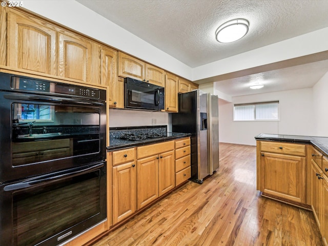 kitchen with black appliances, a textured ceiling, and light hardwood / wood-style flooring