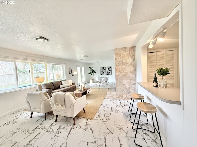 living area featuring marble finish floor, baseboards, and a textured ceiling