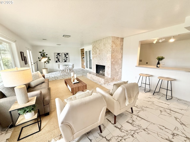 living area with a tile fireplace, marble finish floor, and visible vents