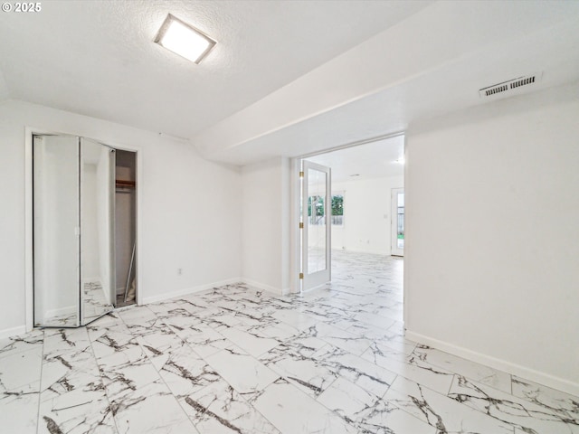 interior space featuring marble finish floor, visible vents, a textured ceiling, and baseboards