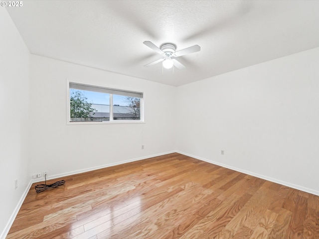 spare room featuring ceiling fan, light wood-style flooring, baseboards, and a textured ceiling