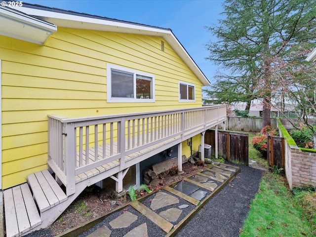 view of side of property with fence, a deck, and central AC unit