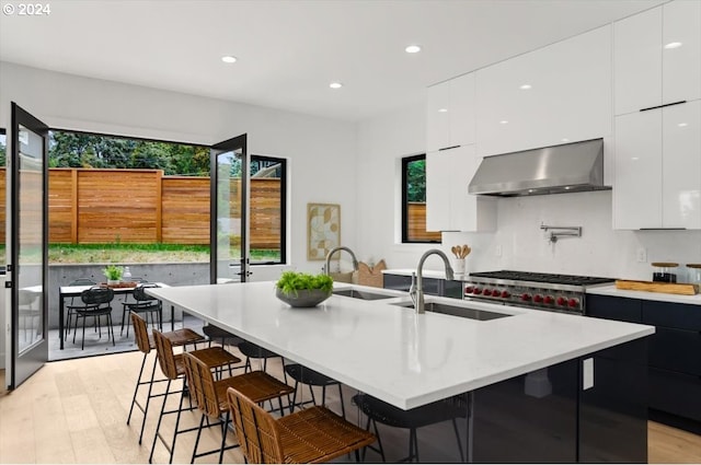 kitchen with a kitchen island with sink, wall chimney exhaust hood, and a wealth of natural light