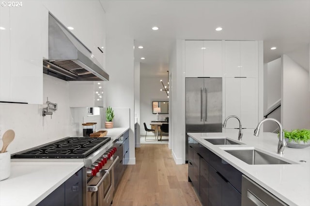 kitchen with light hardwood / wood-style flooring, high end appliances, range hood, and white cabinets