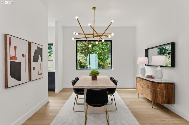 dining room featuring light wood-type flooring, a notable chandelier, and a wealth of natural light