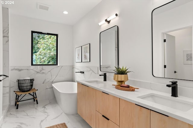 bathroom with tile walls, vanity, and a tub