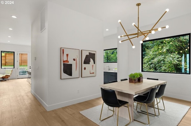 dining area with light hardwood / wood-style floors, sink, and a notable chandelier