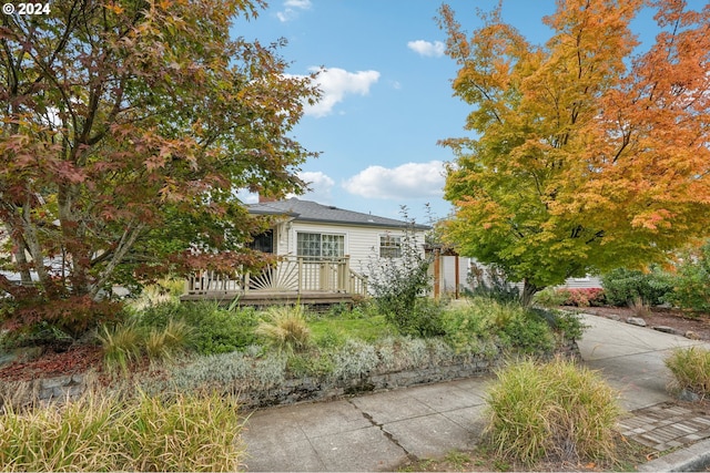 view of property hidden behind natural elements featuring a wooden deck