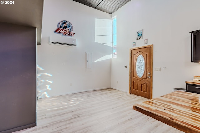 foyer featuring an AC wall unit, electric panel, light hardwood / wood-style flooring, and high vaulted ceiling