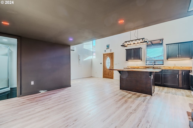 kitchen featuring a kitchen bar, pendant lighting, light hardwood / wood-style flooring, butcher block countertops, and a kitchen island