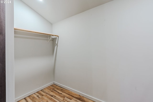 walk in closet featuring light hardwood / wood-style floors and vaulted ceiling