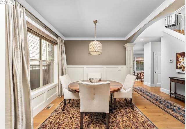 dining area with visible vents, arched walkways, crown molding, light wood finished floors, and decorative columns