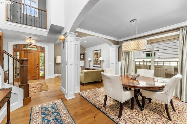 dining area featuring arched walkways, light wood finished floors, baseboards, and ornate columns