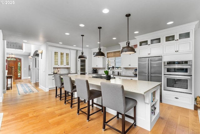 kitchen featuring white cabinetry, light wood-style floors, a spacious island, and stainless steel appliances