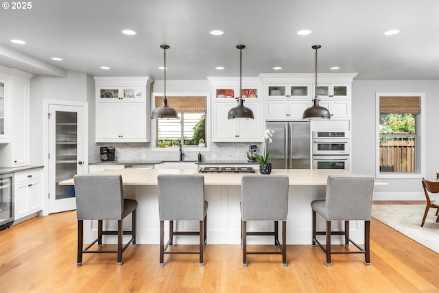 kitchen with a sink, appliances with stainless steel finishes, white cabinets, and light countertops