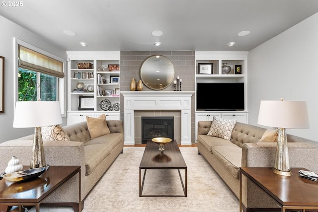 living area featuring a glass covered fireplace, built in features, and recessed lighting