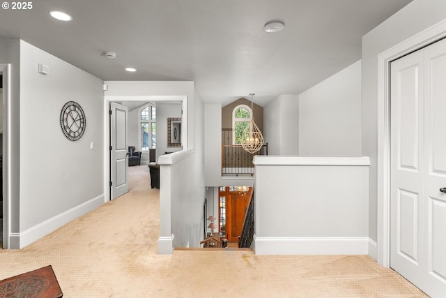 hall featuring baseboards, an inviting chandelier, recessed lighting, carpet flooring, and an upstairs landing