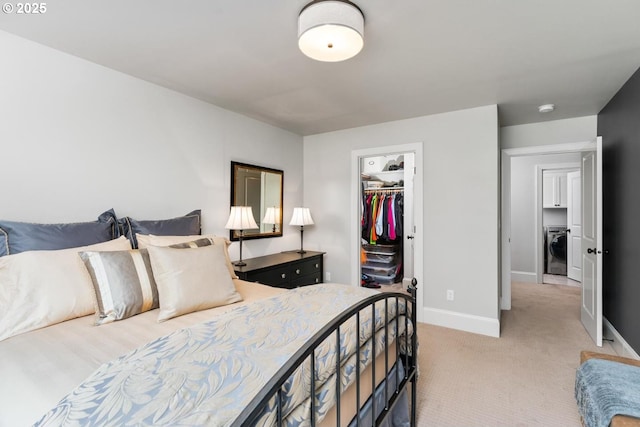 bedroom with a walk in closet, washer / clothes dryer, a closet, baseboards, and light colored carpet