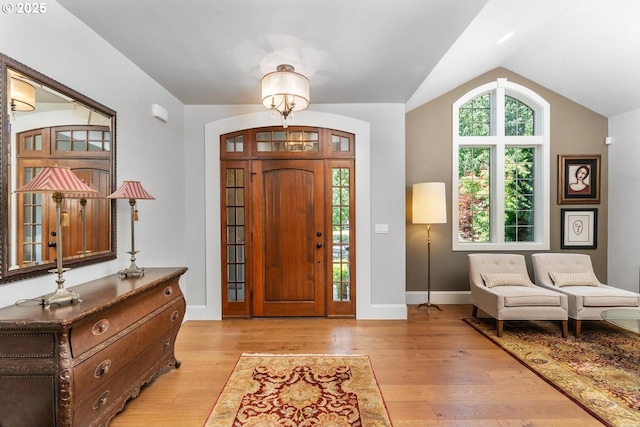 entrance foyer with vaulted ceiling, light wood-style flooring, and baseboards