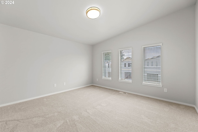 carpeted spare room featuring lofted ceiling